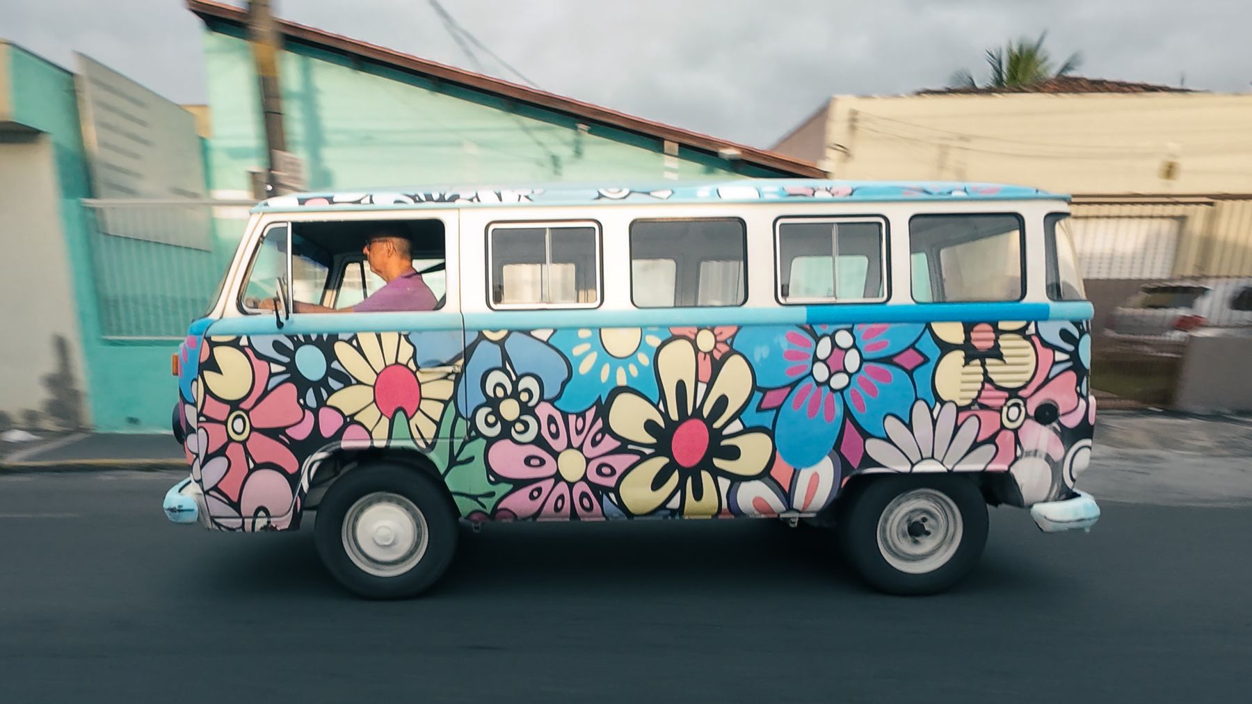 Hand-painted flower-covered Volkswagen van driving through Cruzeiro, Brazil
