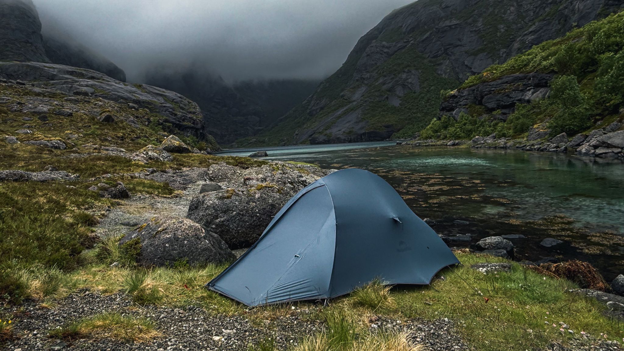 Blue tent in a Lofoten valley, mist on the mountains