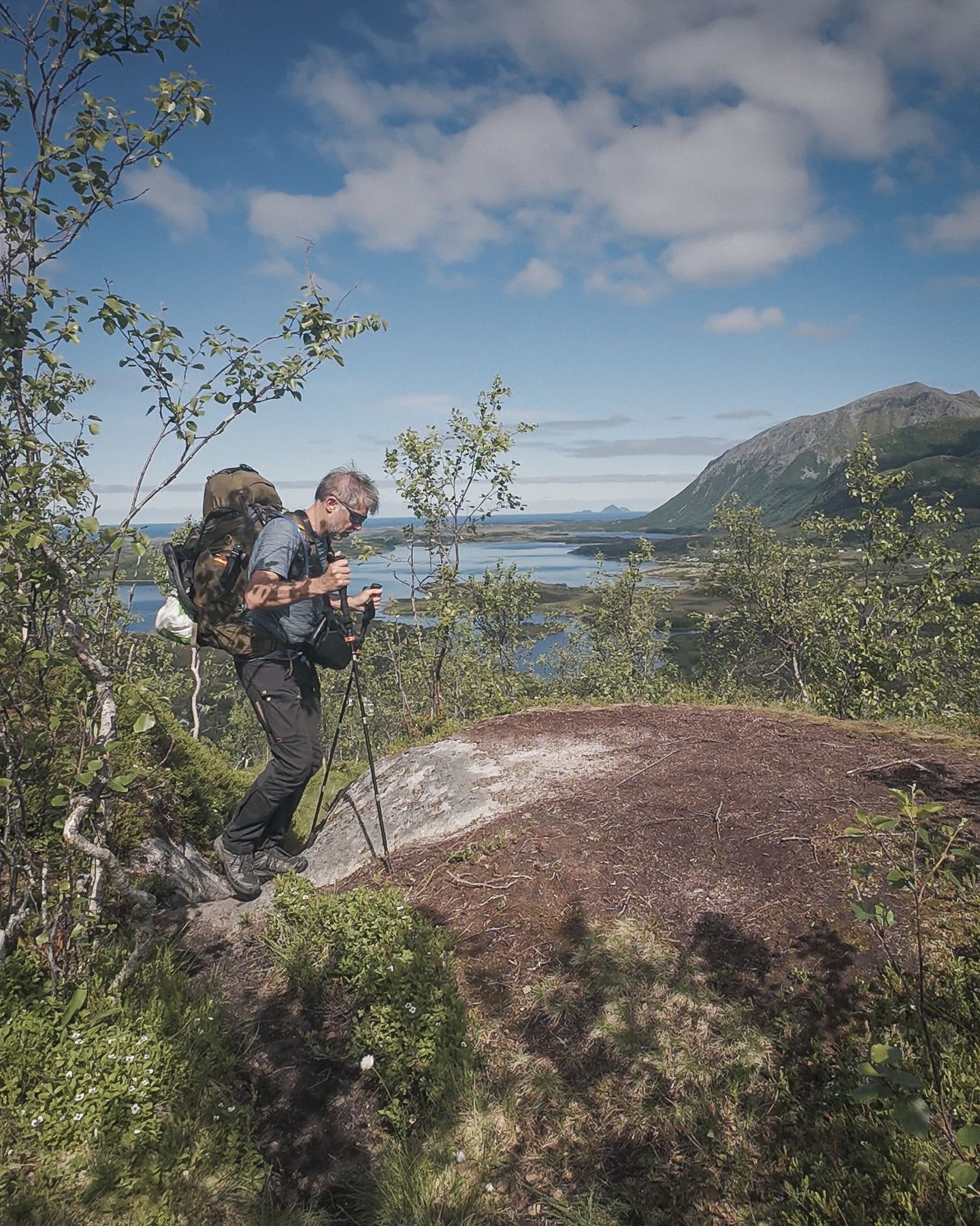 Trekking with a heavy pack on a trail above the sea, Lofoten
